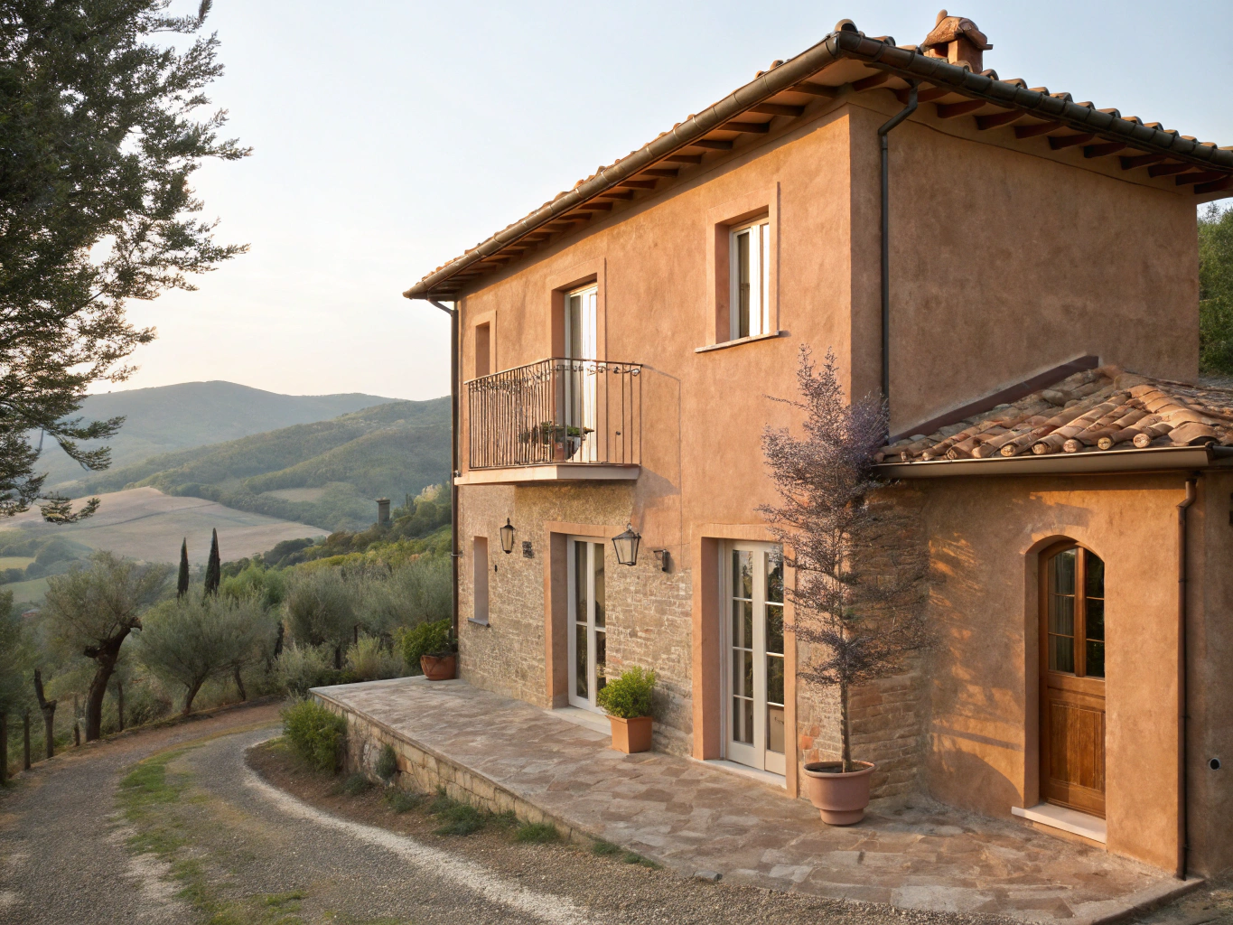 Sunlit stone terrace and facade of Casa Moricciani overlooking the Val d'Orcia valley